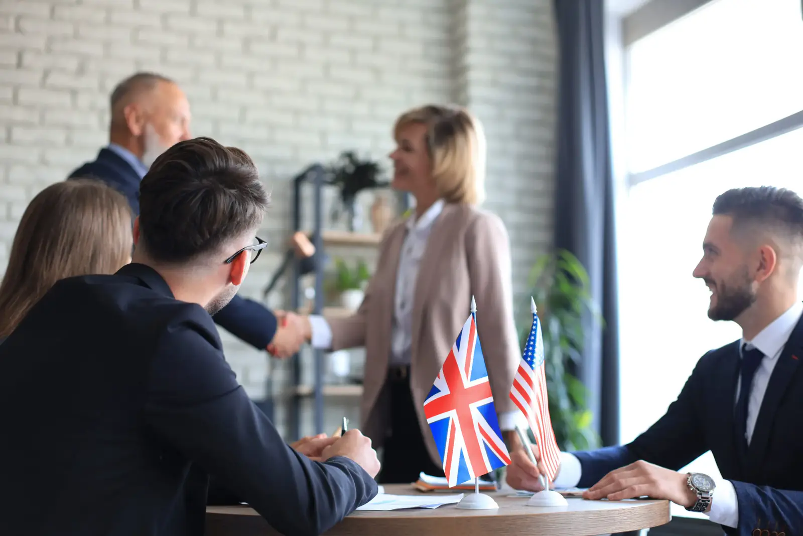 Capacitación en inglés empresarial para equipos de trabajo en una mesa de negociación con banderas internacionales.