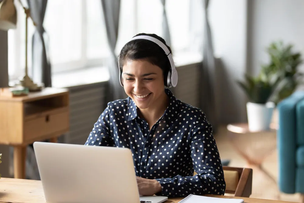Mujer colaboradora en una sesión de capacitación de idiomas en línea para empresas usando auriculares y laptop.