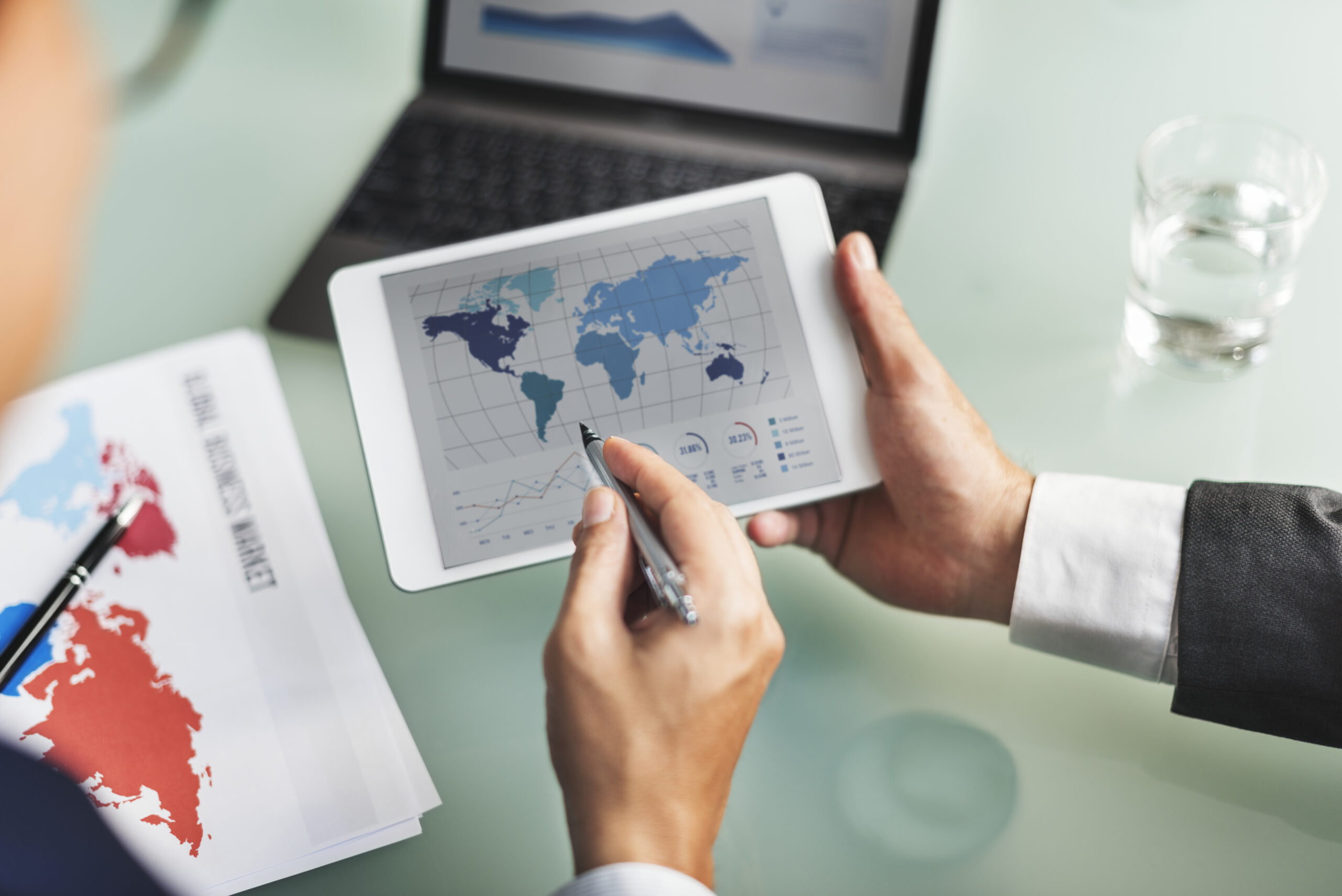 Directivo analizando mapas de comercio global y estrategias de nearshoring en mexico usando una tableta en su oficina.
