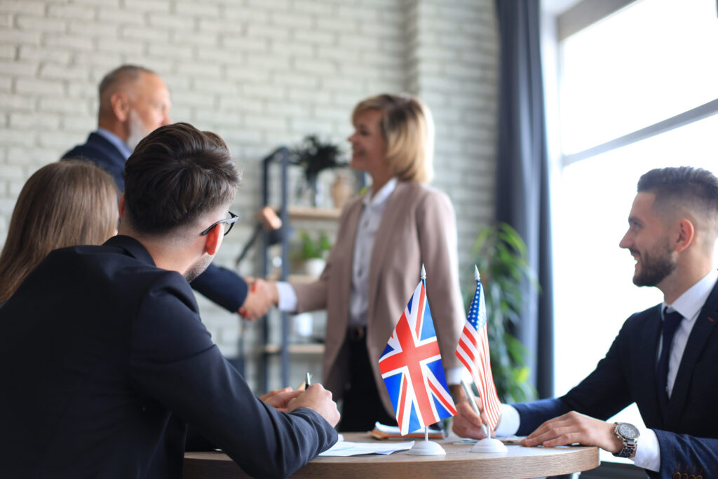 Capacitación en inglés empresarial para equipos de trabajo en una mesa de negociación con banderas internacionales.